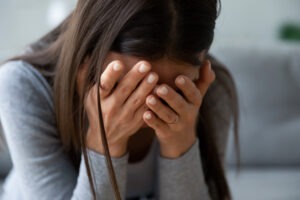 Close,up,unhappy,young,woman,hiding,face,in,hands,,feeling