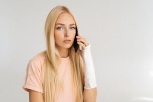 Studio,portrait,of,sad,injured,young,woman,with,broken,arm